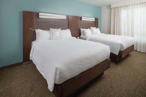 a hotel room with two beds with white sheets at Residence Inn by Marriott Ontario Rancho Cucamonga in Rancho Cucamonga