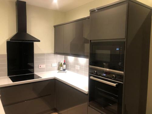 eine Küche mit schwarzen Schränken und einer Mikrowelle in der Unterkunft Modern and comfortable stay in Morecambe in Morecambe