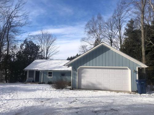 a house with a garage in the snow at Shoreline Pines in Suttons Bay