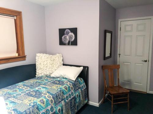 a bedroom with a bed and a chair and a window at Front Cottage "Green Shutter" in Suttons Bay