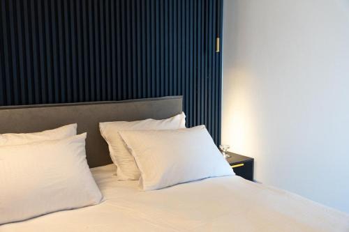 a bed with white pillows and a black wall at Luxury Apartments And Studios At Sea Side By Rently in Eilat