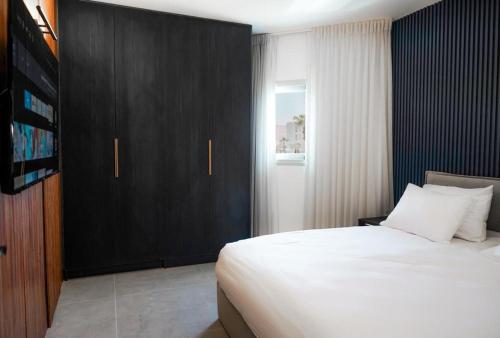 a bedroom with a large bed and a black cabinet at Luxury Apartments And Studios At Sea Side By Rently in Eilat