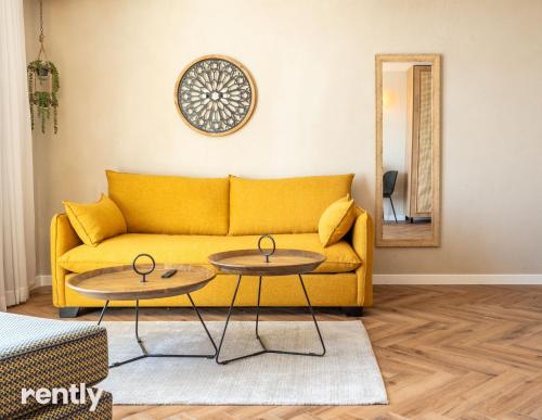 a living room with a yellow couch and two tables at Luxury Apartments And Studios At Sea Side By Rently in Eilat