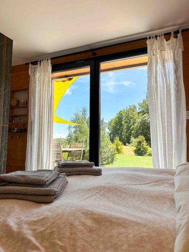 un lit dans une chambre avec une grande fenêtre dans l'établissement Le Chalet du Lys avec jacuzzi, à Les Déserts