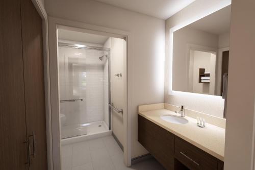 a bathroom with a shower and a sink and a mirror at Staybridge Suites Columbus - Fort Benning by IHG in Columbus