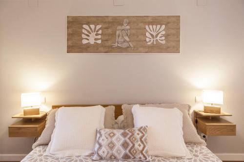a bedroom with a bed with two lamps and a painting on the wall at Apartamento El Espigón (Cimadevilla) in Gijón