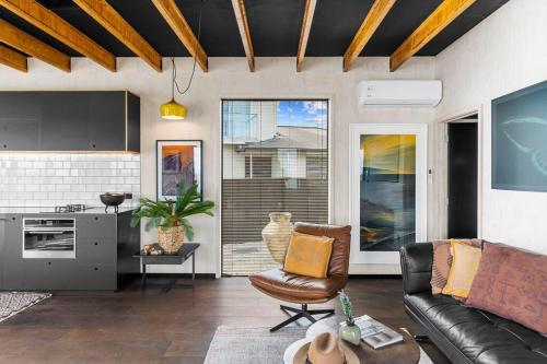 a living room with a couch and a kitchen at Black Hut Eco Retreat in Christchurch