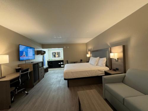 a hotel room with a bed and a couch and a tv at Baymont by Wyndham Corpus Christi Airport in Corpus Christi