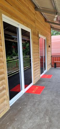 a building with two glass doors and red mats at Habitaciones y Cabañas El Sauce in Tela