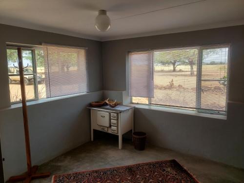 an empty room with two windows and a small table at Wildwasser Farm stay in Hochfeld