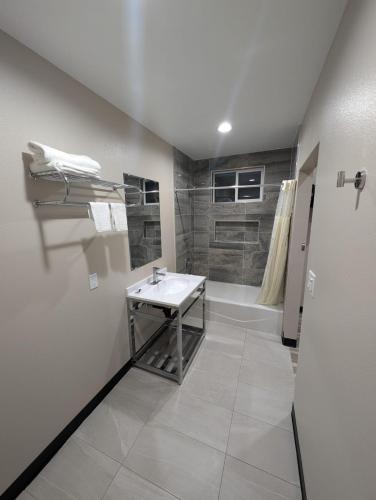 a white bathroom with a sink and a shower at Star Inn Hotel in Maywood