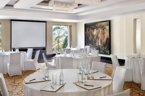 a restaurant with white tables and chairs and a projection screen at Sankara Nairobi, Autograph Collection in Nairobi