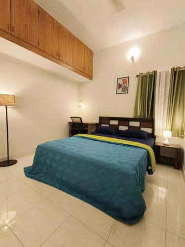 una camera da letto con un letto grande con una coperta blu di HomeStayz Crown a Bangalore