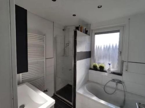 Un baño blanco con bañera y ventana. en Malamin, en Heilbronn