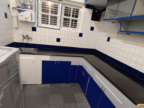 una cucina con pareti piastrellate in blu e bianco di HomeStayz Crown a Bangalore