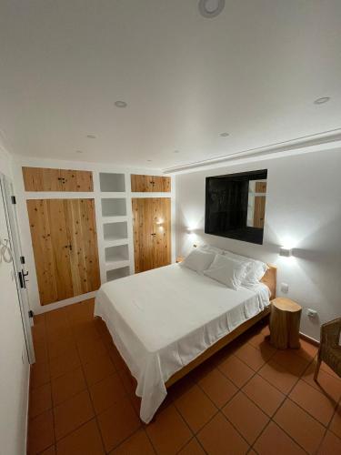 a bedroom with a white bed and a tv on the wall at Mar D'Abstração in Urzelina
