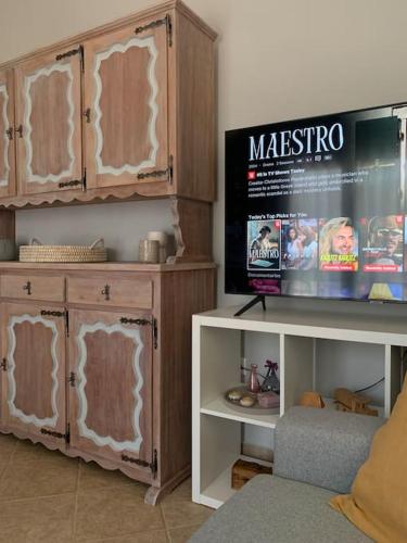 a living room with a tv and wooden cabinets at Nerinalia Residence in Áyioi Apóstoloi