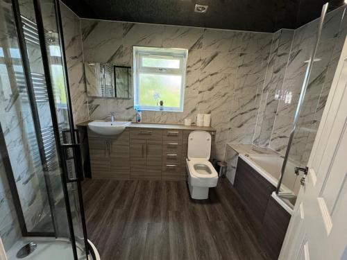 a bathroom with a toilet and a sink and a tub at 5-Bedroom Cottage in New Waltham, Grimsby in Grimsby