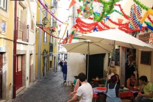 a group of people sitting in an alley with an umbrella at Sweet Alfama, Apartment 2 in Lisbon