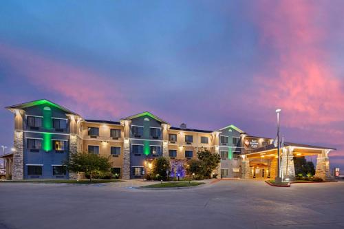 a large apartment building with a parking lot at night at Best Western Plus Emerald Inn & Suites in Garden City