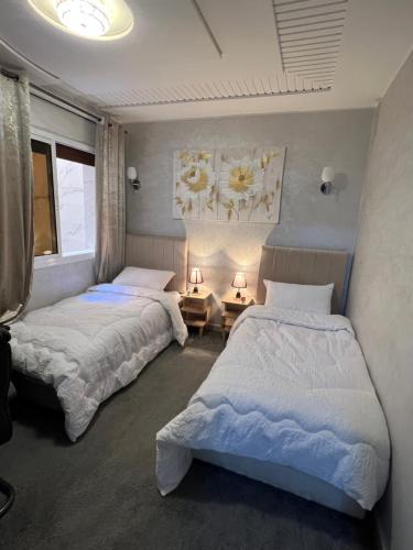 a bedroom with two beds and two tables with lamps at Appartement Moderne à El Qods in Oujda