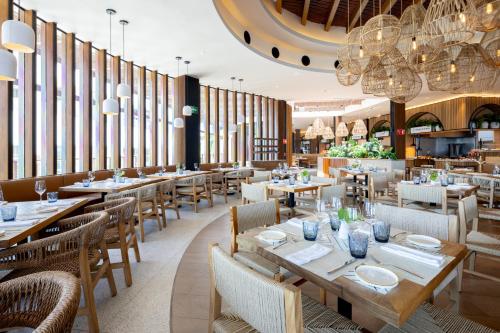 a restaurant with tables and chairs and chandeliers at Hard Rock Hotel Riviera Maya - All Inclusive in Puerto Aventuras