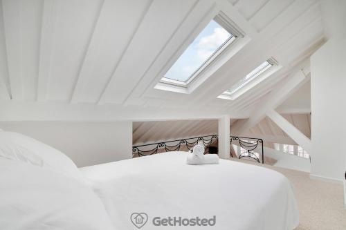 une chambre avec un lit blanc avec une lucarne dans l'établissement Ile de la Cite - Seine & Notre Dame View, à Paris