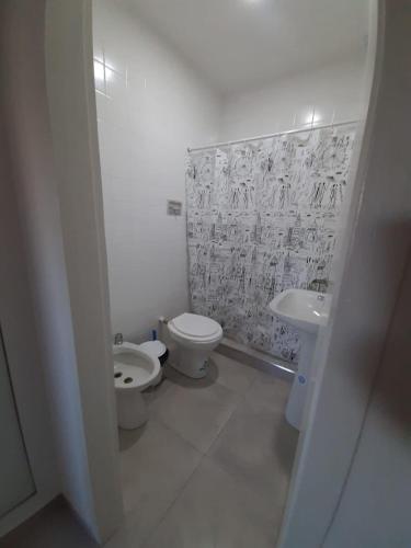 a white bathroom with a toilet and a sink at Depto 41 in Santa Teresita