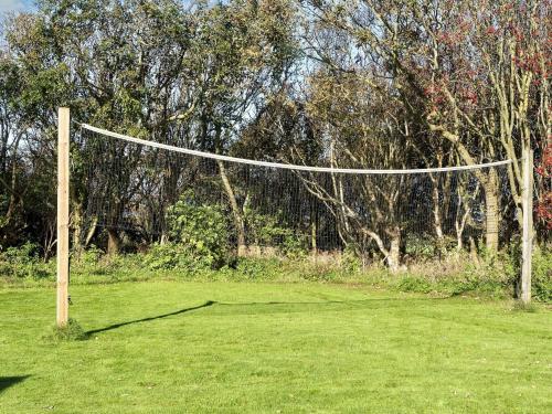 a volley ball net in a field with trees at Scenic Pool House Retreat - By Traum Ferienwohnungen in Thyholm