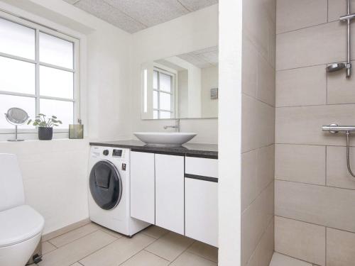 a white bathroom with a washing machine and a sink at Luxury Retreat with Pool in Ulfborg