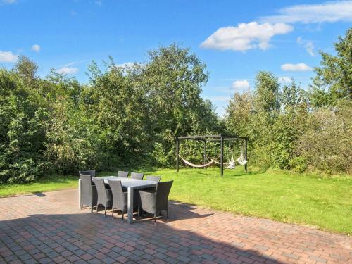a picnic table with chairs and a swing in a park at Luxury Thatched Retreat - By Traum Ferienwohnungen in Ulfborg