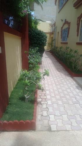 a brick walkway next to a building with a plant at Chez Souleyman et Halimatou in Mbour