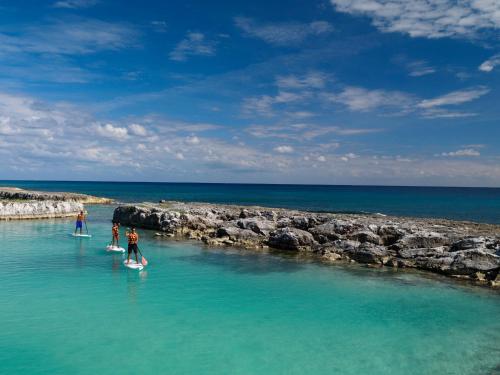 a group of people standing on surfboards in the water at Hard Rock Hotel Riviera Maya - All Inclusive in Puerto Aventuras