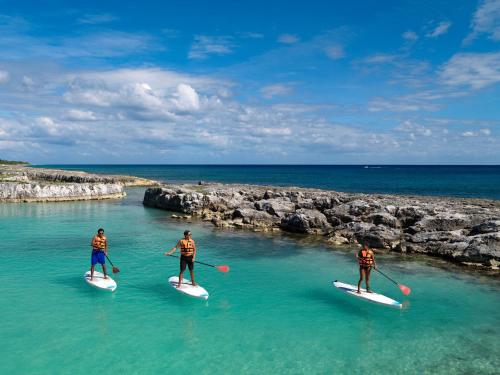 three people are paddling on surfboards in the water at Hard Rock Hotel Riviera Maya - All Inclusive in Puerto Aventuras