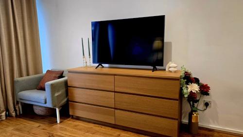 a tv sitting on top of a dresser with a chair at Charming Central london 4 bedroom duplex with private entrance in London