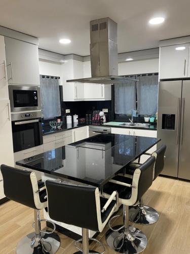 a kitchen with a large black counter with chairs in it at Moradia Activ Mar\Vão in Vila Real