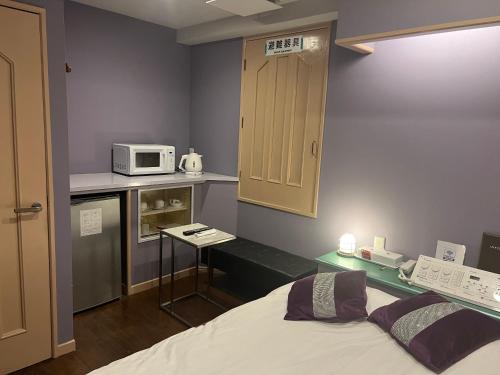 a small kitchen with a bed and a microwave at ホテルシェヌーAdult Only in Tokyo