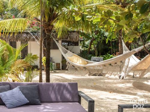 a hammock and a couch on a beach with palm trees at Muita Paz in Atins
