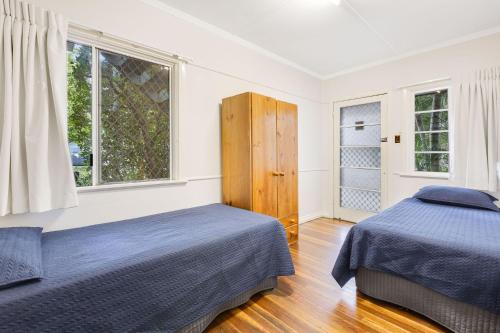 a bedroom with two beds and two windows at Tondio Terrace Flat 3 - Pet Friendly in Gold Coast