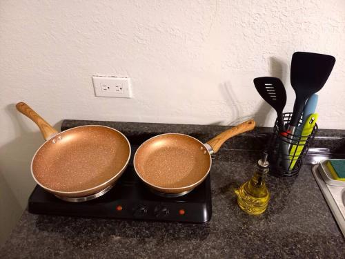 two copper pans sitting on a stove with cooking utensils at Excelente Ubicación Centro Histórico Planta Baja Equipado in Chihuahua