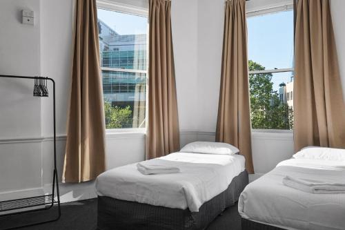 two beds in a room with a window at The Pyrmont Budget Hotel in Sydney