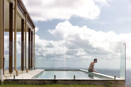 a man sitting in a swimming pool next to a building at Petrichor Estate - 360 Views Pool & Spa in Bald Knob