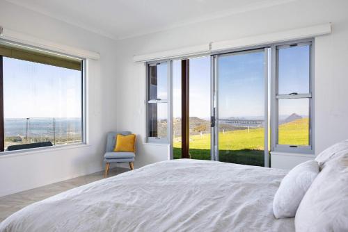 a bedroom with a large bed and large windows at Petrichor Estate - 360 Views Pool & Spa in Bald Knob