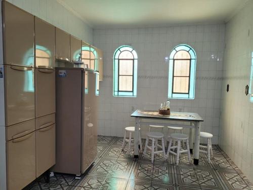 a kitchen with a table and chairs and a refrigerator at Chácara dos Sonhos em Mairiporã in Mairiporã