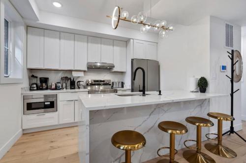a kitchen with white cabinets and gold bar stools at Capitol Hill 3 Charming Townhouse in Downtown DC with Modern Kitchen with Rooftop views in Washington, D.C.