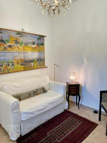 a white couch in a living room with a painting on the wall at Villa Salina - Vicina al mare con giardino privato in Trabia