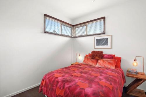 a bedroom with a bed with a red comforter and a window at Aireys Oasis in Aireys Inlet