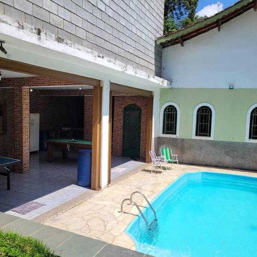 a swimming pool in front of a building with a pool table at Chácara dos Sonhos em Mairiporã in Mairiporã