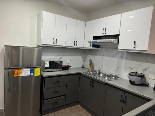 a kitchen with white cabinets and a stainless steel refrigerator at M&J apartment in Cuenca
