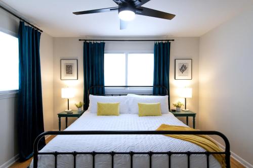 a bedroom with a bed with blue curtains and a ceiling fan at Vintage Modern Mid-Century Gem in Omaha
